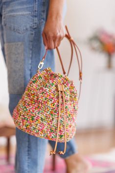 a person holding a handbag with sprinkles on it and wearing blue jeans