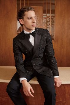 a man in a tuxedo sitting on a counter