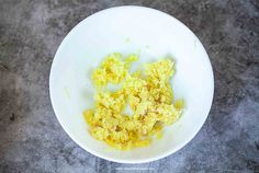 scrambled eggs in a white bowl on a gray counter top with an orange peel sticking out of the side