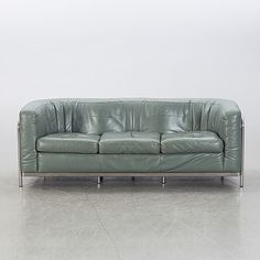 a green leather couch sitting on top of a white floor