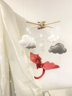 a baby crib mobile with clouds and stars hanging from it's sides, in front of a white curtain