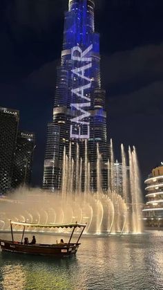 a boat is in front of a large fountain with water shooting up from it's sides