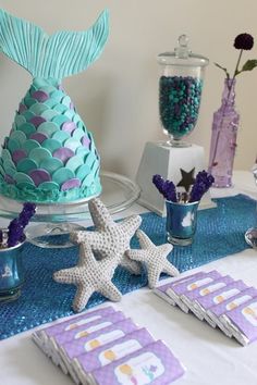 a table topped with blue and purple decorations next to a vase filled with starfish