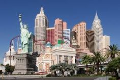 the statue of liberty stands in front of tall buildings and palm trees on a sunny day