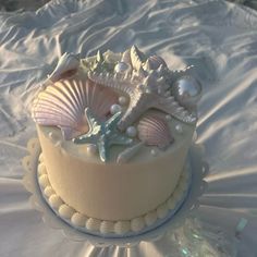 there is a cake decorated with seashells on the table