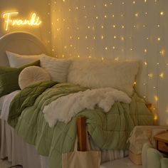 a bed with green comforter and white pillows in a room decorated with string lights