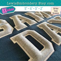 the letters are made out of denim and have white stitching on them, as well as some type of lettering