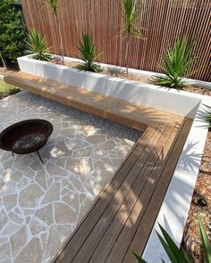 a wooden bench sitting on top of a stone floor next to a planter filled with succulents