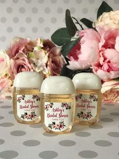 three personalized baby shower gels sitting on a table with pink flowers in the background