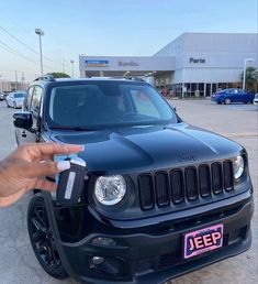 a jeep is parked in a parking lot and someone is holding the keys to it