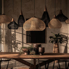 a wooden table topped with vases and plants next to a wall covered in hanging lights