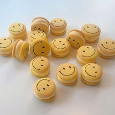 a bunch of yellow macaroons with faces drawn on them are arranged in the shape of smiley faces