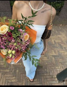 a woman walking down the street holding a bouquet of flowers