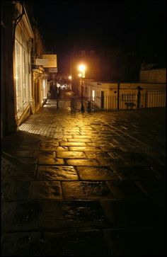 an empty cobblestone street at night with lights on