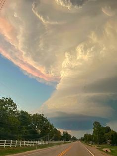 an image of a storm coming in from the sky with some clouds above it and cars driving down the road