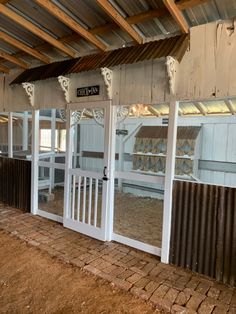 the inside of a horse barn with white doors and brick flooring on each side