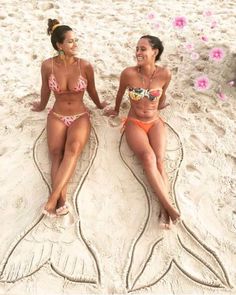 two women in bikinis sitting on the beach