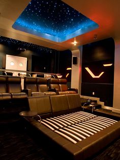 an empty theater room with leather seats and stars on the ceiling, in front of a projector screen