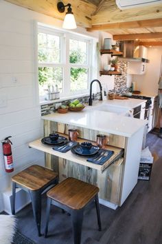 a kitchen with a stove top oven sitting next to a sink and two wooden stools