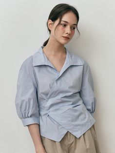 This is We’Dee’s shirt features a clean look with an asymmetrical design that adds a unique touch. The front has two buttons for easy wear and removal, serving as a focal point of the look.- Perfect for daily wear- Can be paired with different styles of bottoms to create various looks- The clean design makes it easy to style with any outfit Casual Asymmetrical Top With Button Closure, Asymmetrical Shirt Outfit, Asymmetrical Summer Tops With Button Closure, Summer Asymmetrical Tops With Button Closure, Asymmetrical Tops With Button Closure For Spring, Spring Asymmetrical Tops With Button Closure, Modern Tops With Buttons For Office, Modern Office Tops With Buttons, Asymmetrical Work Tops With Button Closure