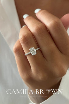 a woman's hand with a diamond ring on her finger and the words camila brown written below it