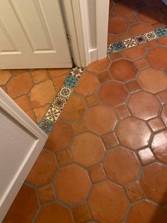 a bathroom with an orange and blue tile floor next to a white door on the other side