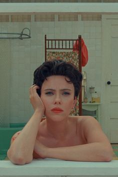 a woman sitting in a bathtub with her hand on her head