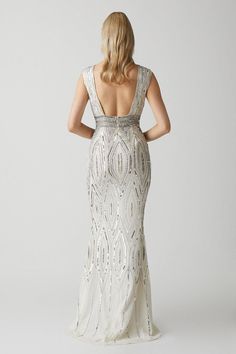 the back of a woman wearing a white dress with silver beading and sequins