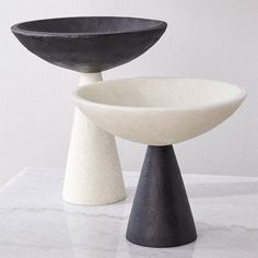 two black and white bowls sitting on top of a table