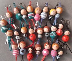 many small wooden toys are arranged together on a table top with keychains in the shape of people's heads