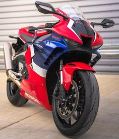 a red, white and blue motorcycle parked in front of a building