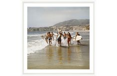 a group of people running into the ocean with surfboards