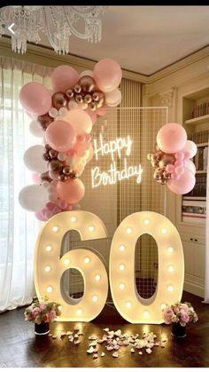 a birthday sign with balloons and lights in the shape of the number 60 on it