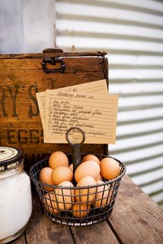 eggs in a basket next to an old wooden box with writing on it and a bottle of milk