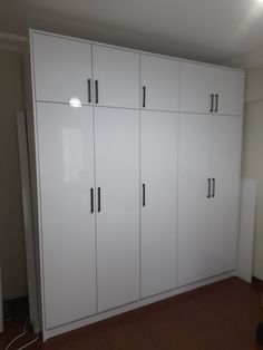 an empty room with white cupboards and wood flooring in the middle of it