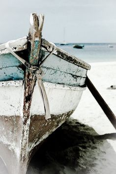 a boat sitting on top of a sandy beach