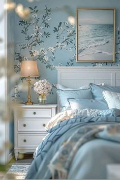 a bedroom decorated in blue and white with flowers on the wall, bedding and nightstands