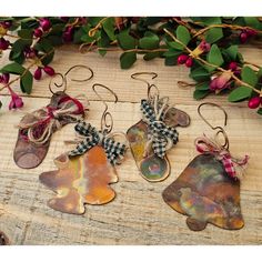 four metal leaf ornaments hanging from hooks on a wooden table