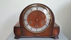 an old wooden clock with roman numerals on the face sits on a table