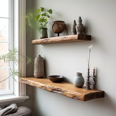 two wooden shelves with vases and other items on them in front of a window