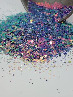 a scoop full of colorful confetti sprinkles sitting on top of a table