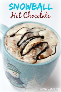 hot chocolate in a blue mug topped with whipped cream and chocolate drizzles