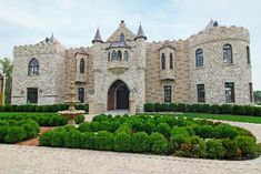 a large castle like building with lots of windows and bushes in front of the entrance