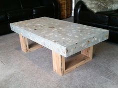 a coffee table made out of pallet wood in a living room with black leather couches