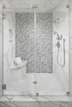 a bathroom with marble walls and flooring in the shower area, along with a glass door