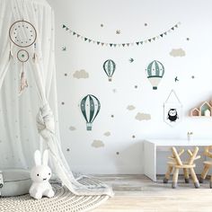 a child's room decorated in green and white with hot air balloons on the wall