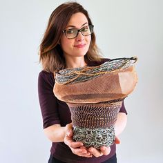 a woman is holding a basket made out of yarn and other things in her hands