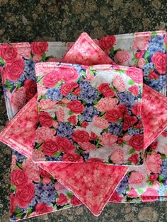 four pink and blue flowers are sitting on a tablecloth with two napkins in front of them