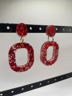 Looking for a bold statement earring? These bright red glitter oval acrylic stud earrings are perfect. Not only are they lightweight, they're also hypoallergenic due to the nickel free gold colored jump rings and push back earring backs. And the best part? The red glitter is embedded in the resin so there's no risk of shedding it everywhere! These earrings are fun, bold, and perfect for someone who loves to stand out! Red Glitter Party Earrings, Red Glitter Earrings For Party, Red Glitter Jewelry For Party, Glitter Red Earrings For Gifts, Red Glitter Earrings For Gift, Trendy Red Resin Earrings, Trendy Oval Party Earrings, Trendy Oval Earrings For Party, Statement Earring