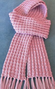 a pink knitted scarf laying on top of a table